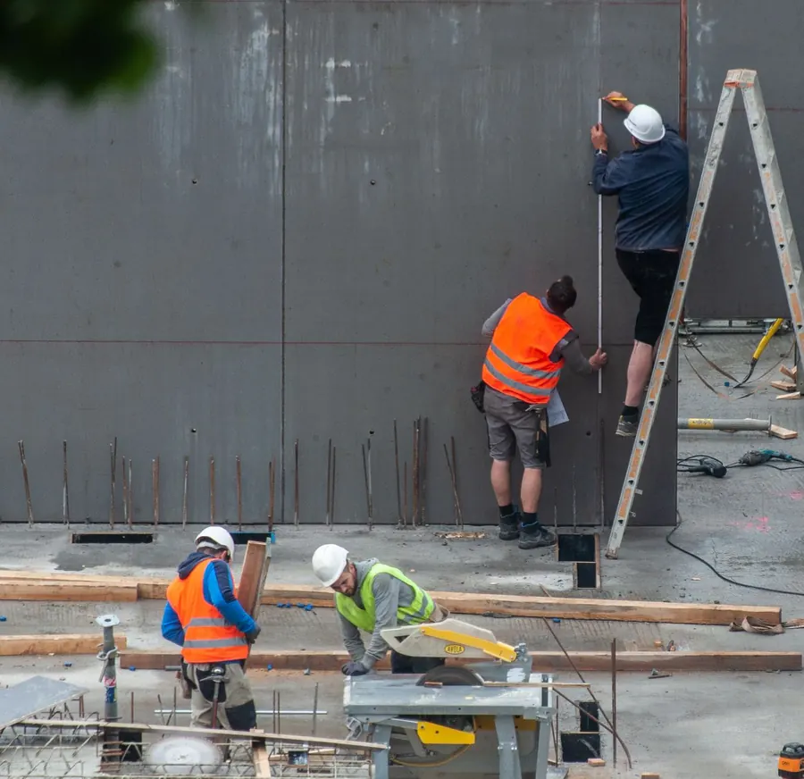 Obreros midiendo y ajustando paneles de formaleta en una obra de concreto