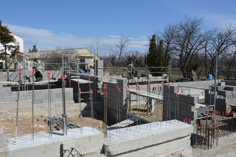 Obreros trabajando sobre la fundación de concreto de una vivienda