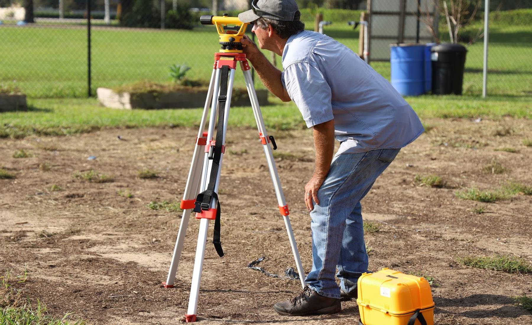 Un agrimensor realiza mediciones con su nivel topográfico en un solar tropical