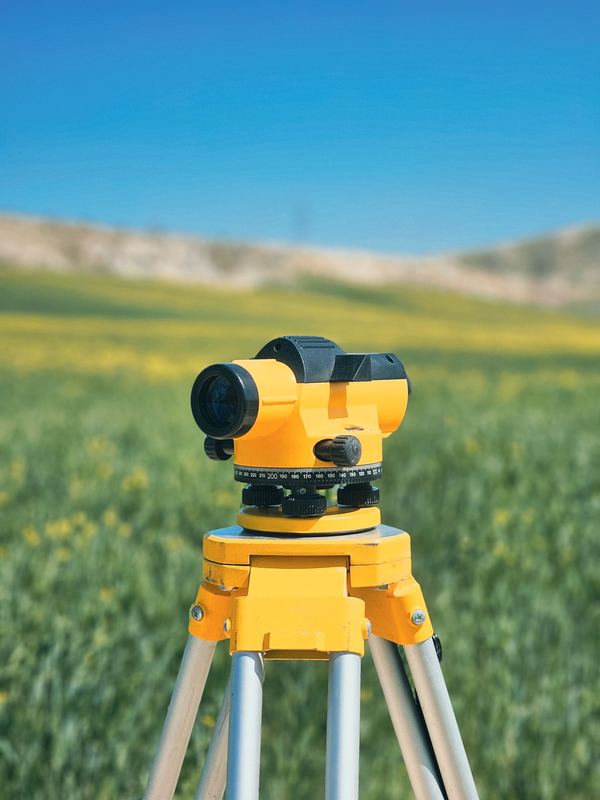 Nivel topográfico amarillo sobre trípode en un campo verde
