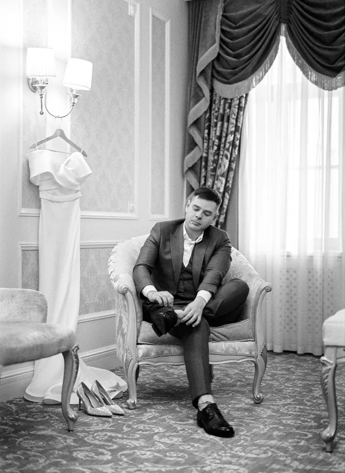 Novio anudándose los zapatos antes de la ceremonia, fotografía de referencia en blanco y negro