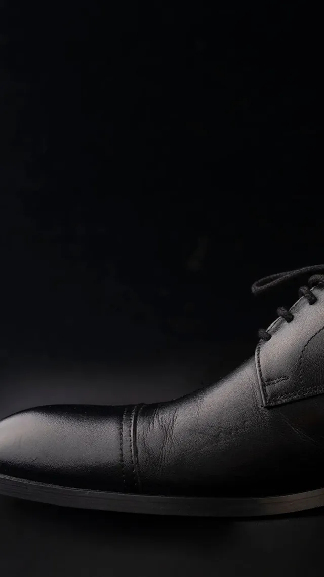 Zapato Oxford negro clásico sobre fondo oscuro, fotografía de referencia