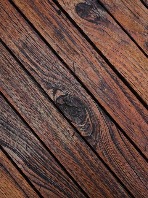 Tablones de madera oscura en diagonal, con la veta y los nudos marcados por una luz rasante