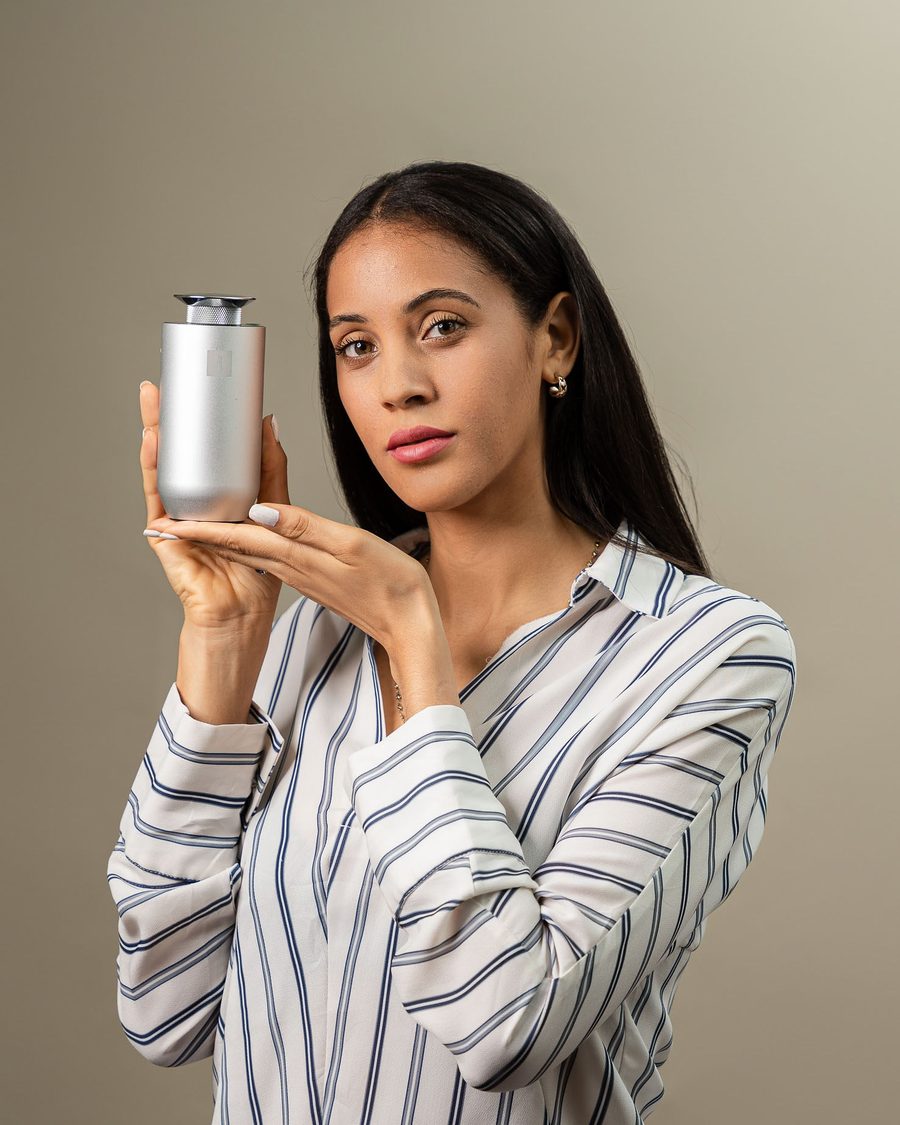 Mujer sosteniendo un difusor cilíndrico plateado de Alto Essences
