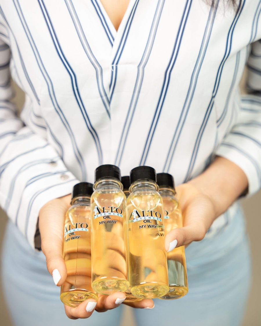 Manos sosteniendo cinco frascos de aceite aromático Alto Oil