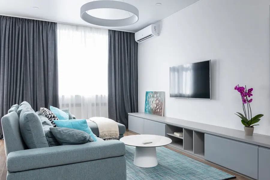 Sala de estar en tonos grises y celestes con un aire acondicionado split en la pared
