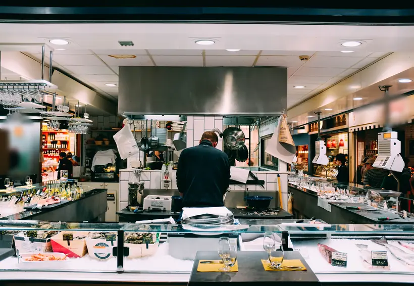 Mostrador refrigerado de un restaurante con la cocina de acero inoxidable al fondo
