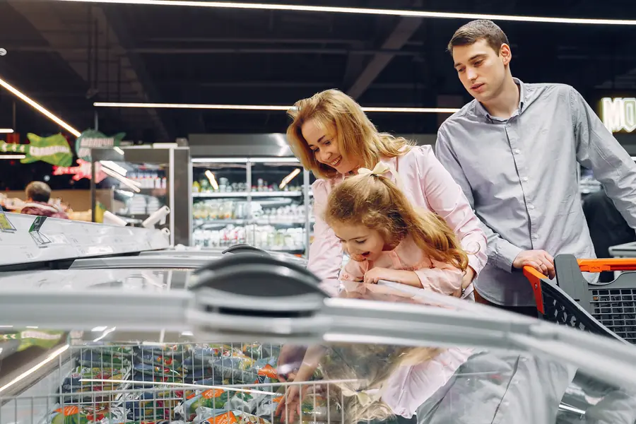 Freezer horizontal de supermercado con una familia eligiendo productos congelados