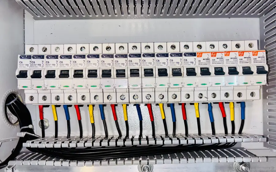 Fila de breakers en un tablero eléctrico con el cableado ordenado y codificado por colores