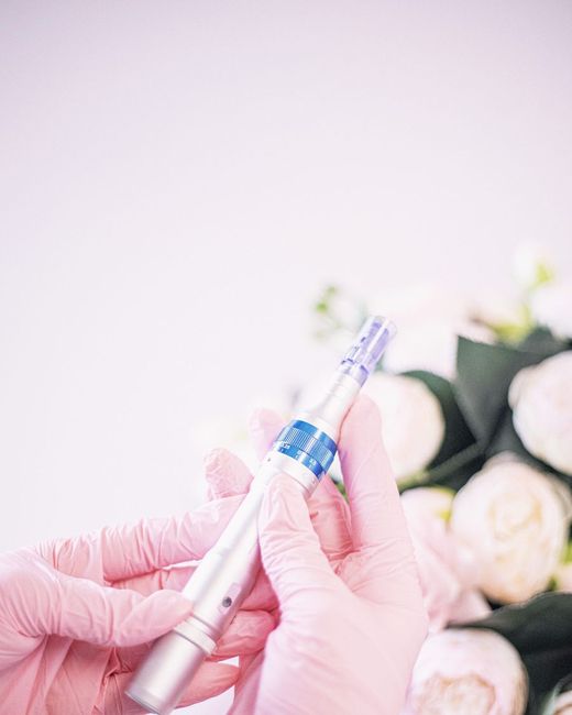 Esteticista con guantes aplicando un cabezal dorado sobre la mejilla de una clienta