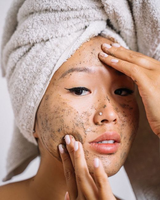 Mujer retirándose una mascarilla facial oscura con las manos