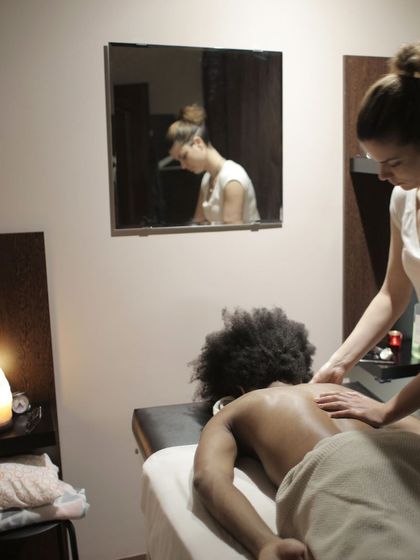 Masaje de espalda en una cabina con espejo, velas y luz cálida