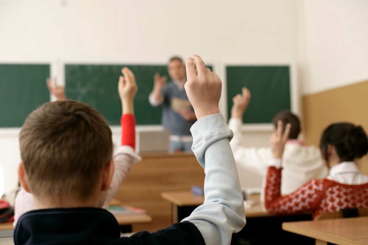 Niños levantando la mano en un aula