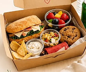 Caja kraft con sándwich, frutas, galleta y snacks, lista para entregar