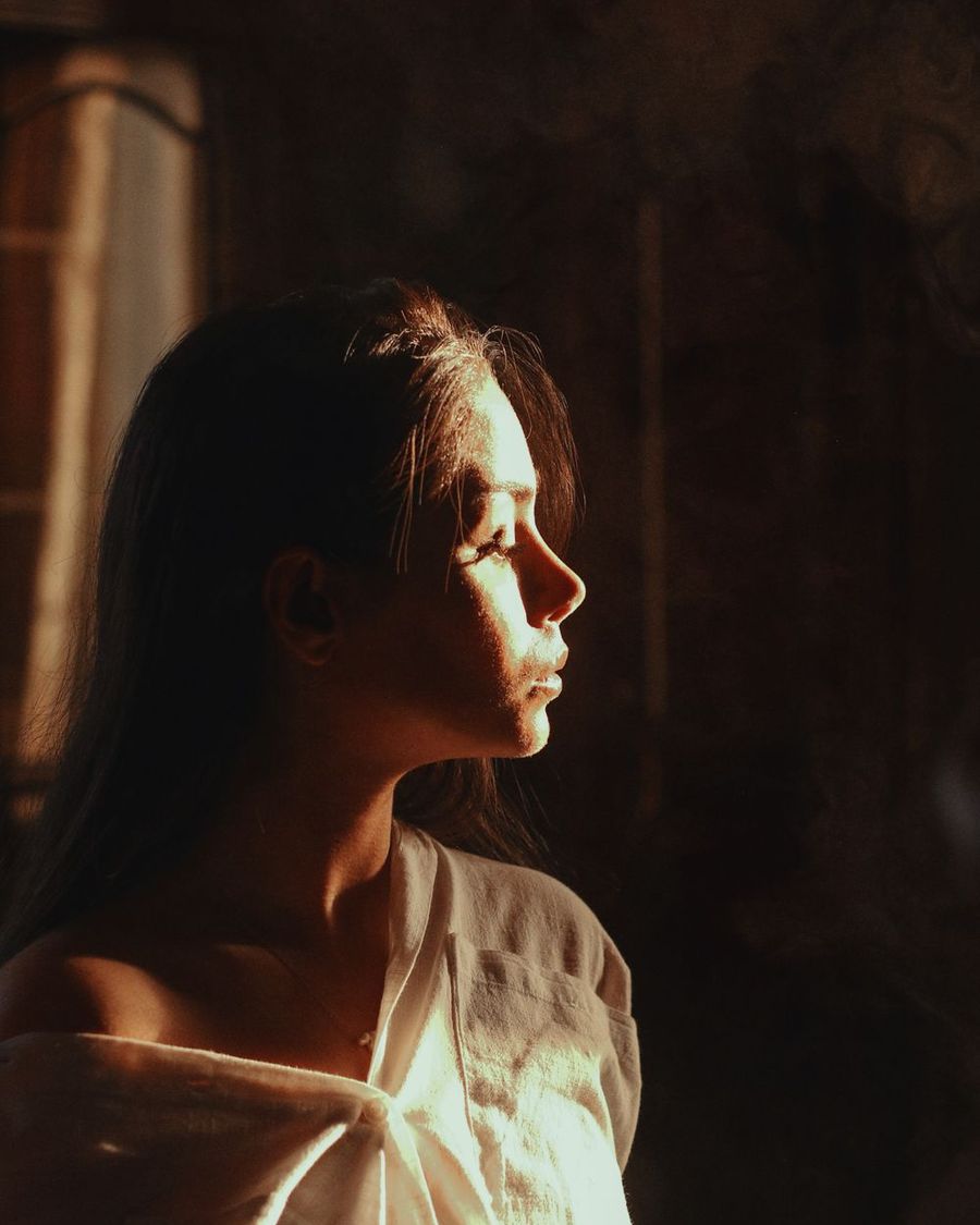 Retrato sereno de una mujer de perfil, iluminada por una luz cálida (fotografía de referencia)