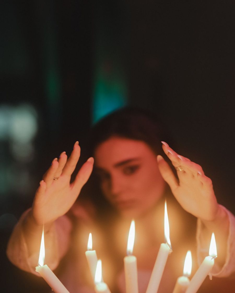 Manos serenas ante la luz cálida de unas velas, en un gesto de introspección