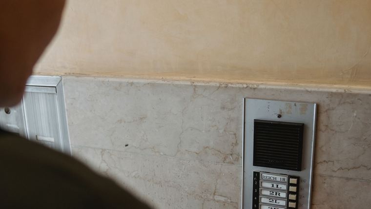 Persona utilizando el intercom de un edificio