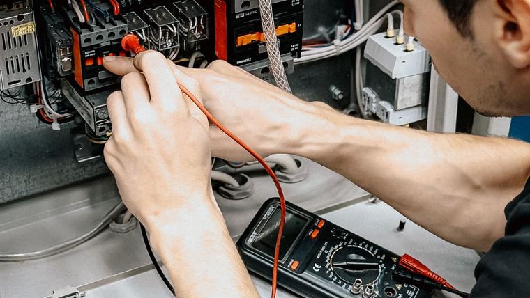 Electricista midiendo un panel eléctrico con multímetro