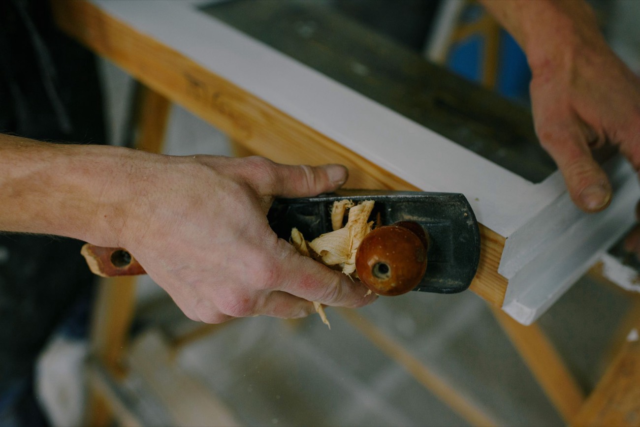 Manos de un ebanista cepillando madera en el taller
